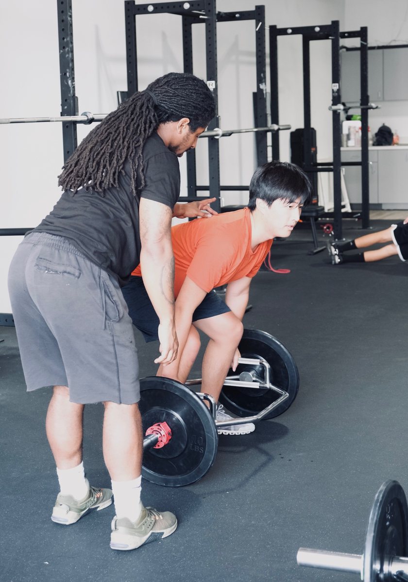 A Virtus coach cueing an athlete through a trap bar deadlift