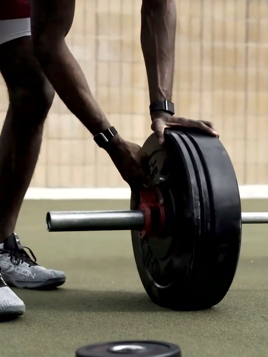 An adult athlete loading a bumper plate onto a barbell
